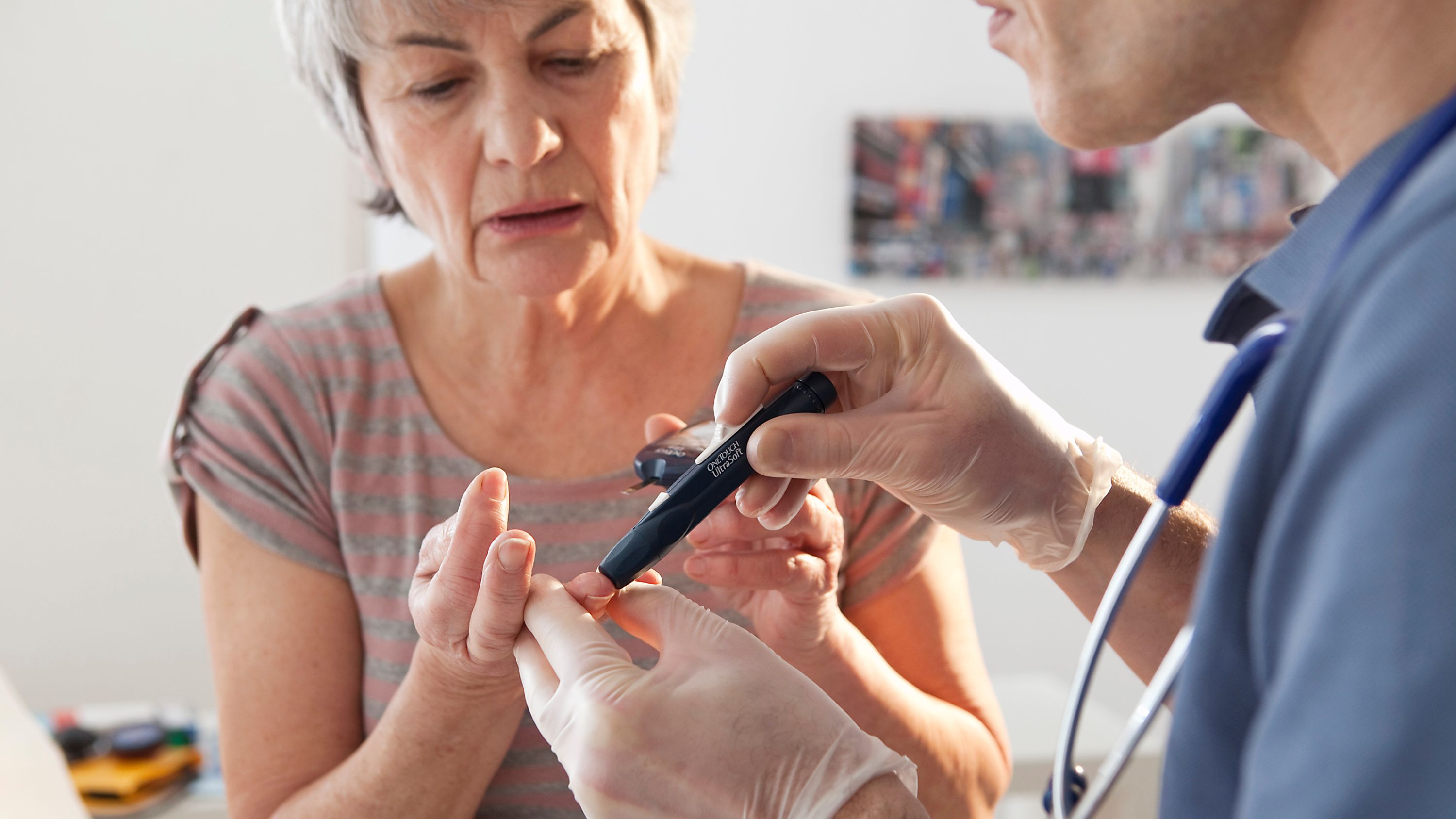 Ein Arzt nimmt einer Diabetes Patientin Blut ab.
